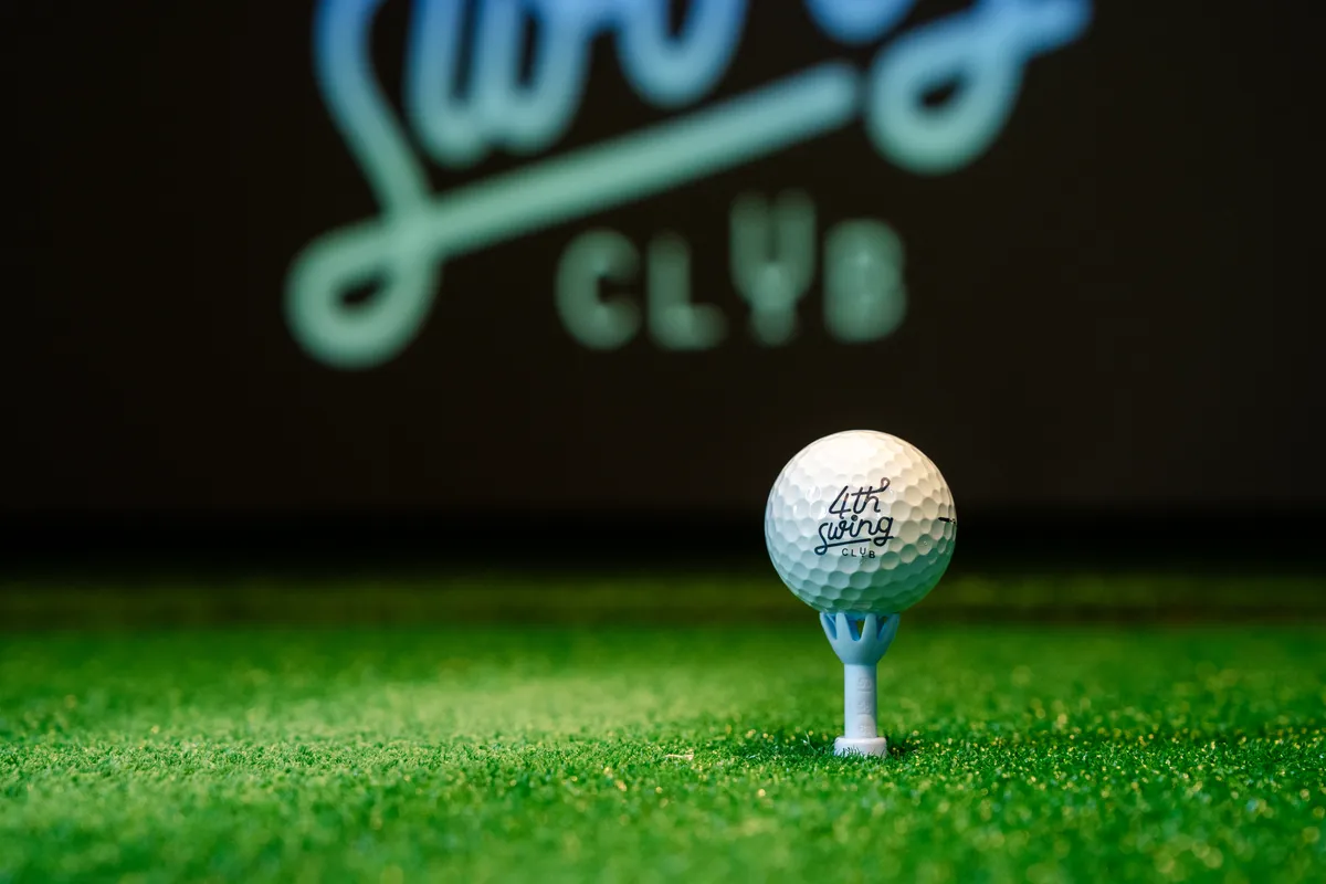 ลูกกอล์ฟพิมพ์โลโก้ 4th Swing Club วางบนทีบนพื้นหญ้าเทียม