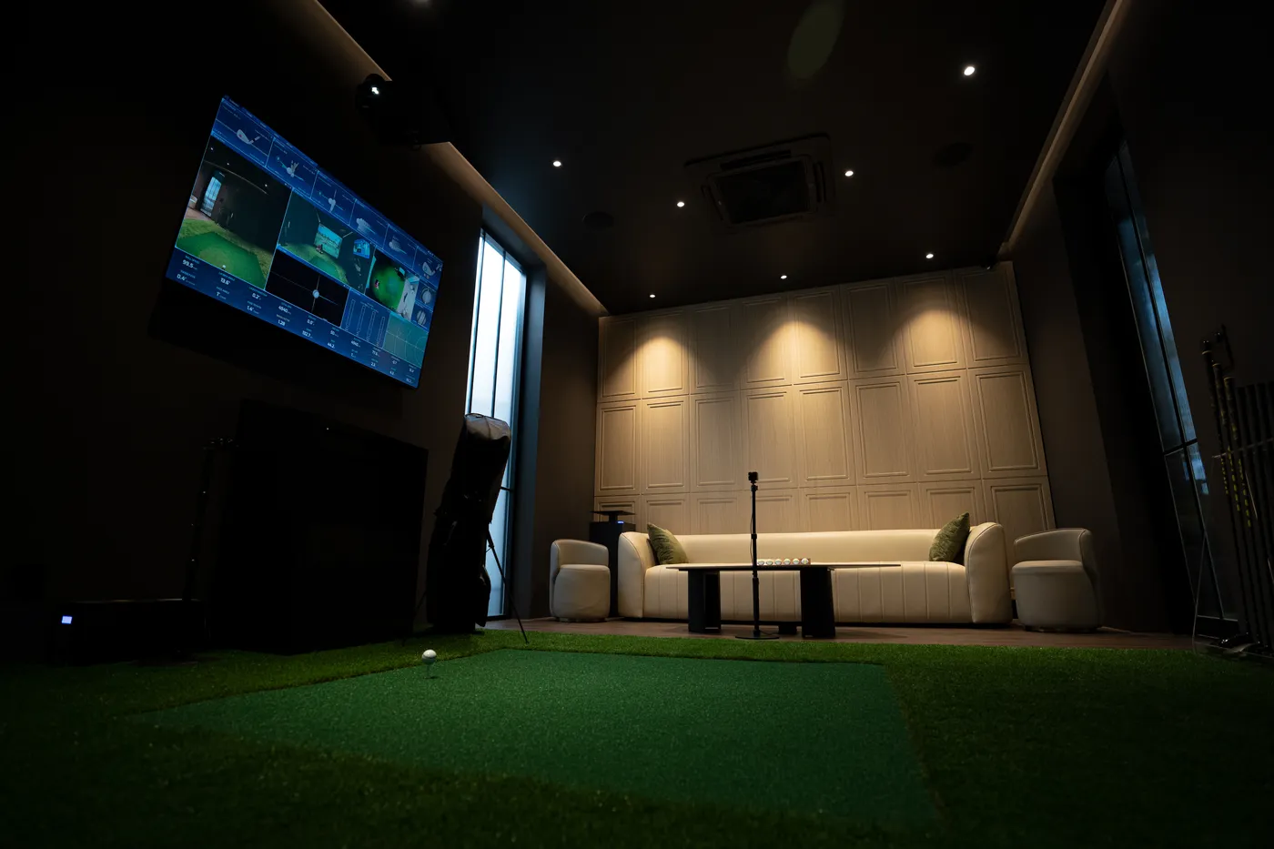 ห้อง Course A ของ 4th Swing Club มีโซฟาหนังสีครีม โต๊ะกลาง และพื้นซ้อมพัตต์